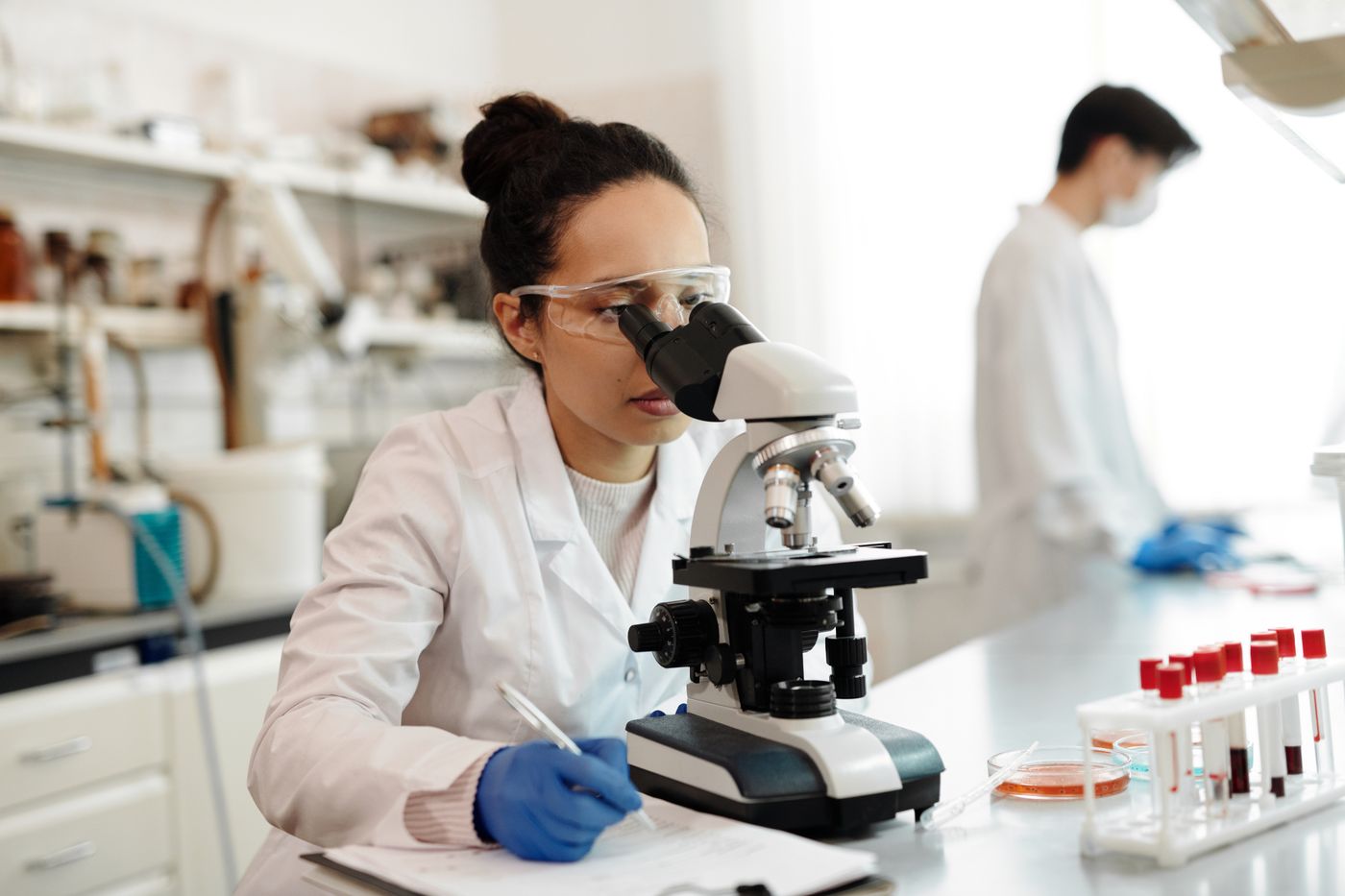 A scientist studying a sample under a microscope in a bright laboratory