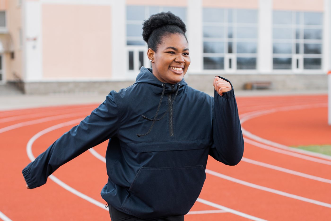 A joyful woman jogging on a coral running track
